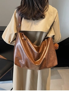 Sac fourre-tout en cuir marron avec large bandoulière et breloque ours sur modèle