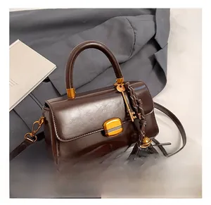 Detail of dark brown leather handbag featuring a golden buckle and key pendant accessory