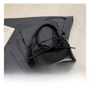 Détail d'un sac à main en cuir noir brillant avec un grand nœud et logo VGONGZHU