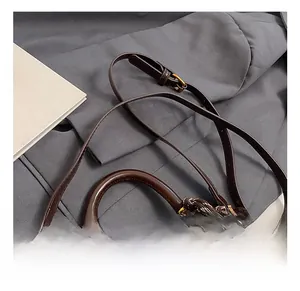 Detailed close-up of dark brown polished leather bag with golden hardware and charm