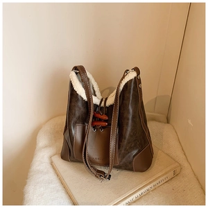 Detailansicht der braunen Bucket-Bag mit weißem Fleece-Besatz und Holz-Hornknopfverschluss
