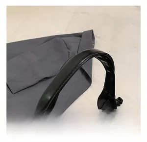 Détail de la poignée en cuir ciré noir du sac à main avec des coutures renforcées et une texture