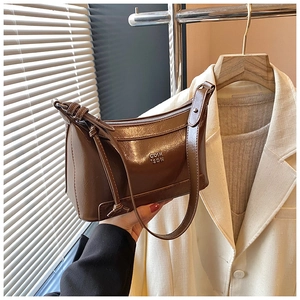 Macro shot of brown leather pillow bag with silver letters and sleek shoulder strap