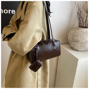 Brown rectangular shoulder bag with small coin purse shown on a model in a trench coat
