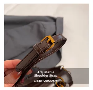 Detail showing the adjustable dark brown leather shoulder strap with gold buckle