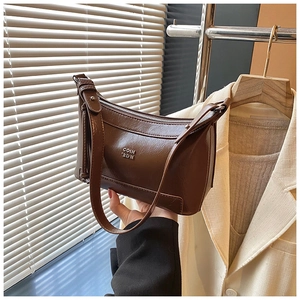 Detail of a brown vintage faux leather shoulder bag with a metallic logo and zipper