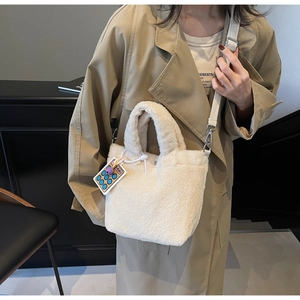 Detail of cream plush bucket bag showing fluffy faux fur texture and adjustable strap