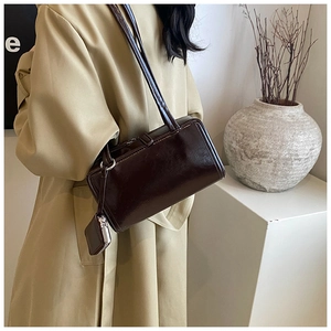 Detail view of coffee patent leather shoulder bag with matching square charm pouch accessory
