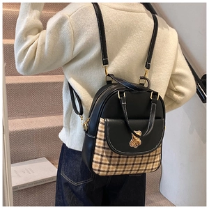 Detail of checkered patchwork backpack featuring a golden bear clasp and top handle