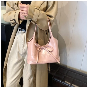 Vue détaillée du sac à bandoulière rose avec nœud et texture gaufrée sur cuir brillant
