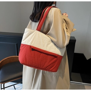 Side view of large cream and red contrast tote bag carried by a model for daily use