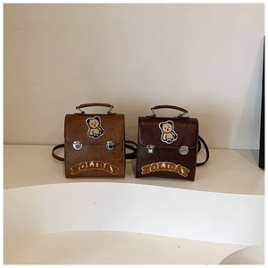 Detail of vintage faux leather backpacks with plush bear patches and Holiday lettering