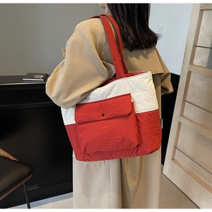 Detail of red and white tote bag with front flap pocket shown on model shoulder
