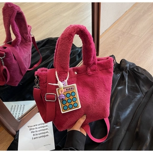 Detail of plush fuchsia bucket bag with soft faux fur texture and calculator charm