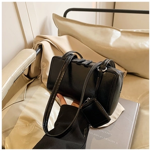 Detail showing the glossy black crossbody bag with double zippers and small coin pouch
