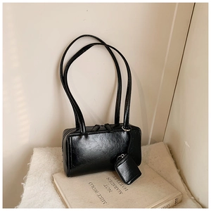 Detail of a vintage black glossy leather shoulder bag with a matching mini coin pouch charm
