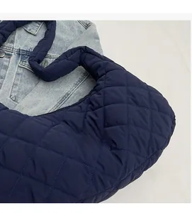 Detail of dark blue quilted nylon shoulder bag showing puffy diamond lattice texture