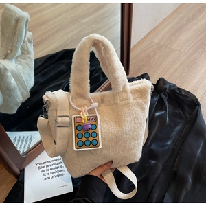 Close-up of cream plush bucket bag with fuzzy handles and a cute calculator charm