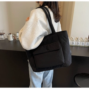 Macro shot of large black padded tote bag with front flap pocket in cafe setting