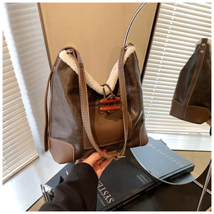 Detail der braunen Wildleder-Beuteltasche mit beigem Lammfellbesatz und Knebelverschluss