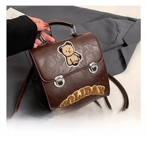 Detail of dark brown retro faux leather backpack featuring bear and holiday embroidery