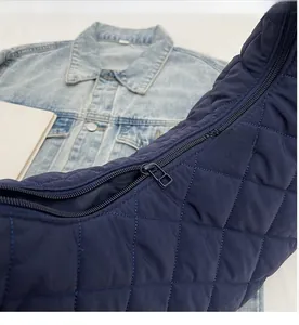 Detail view of smooth metal zipper and quilted nylon texture on the dark blue shoulder bag