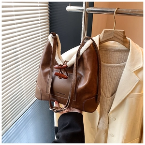 Detail der braunen Ledertasche mit weißem Lammfellbesatz und hölzernen Hornknöpfen