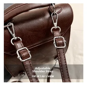Detail of adjustable shoulder strap with silver hardware on a brown lychee grain backpack