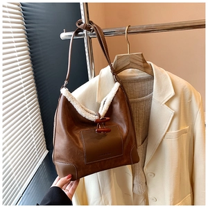 Detailansicht der braunen Ledertasche mit weißem Lammfellbesatz und Knebelknopf-Verschluss