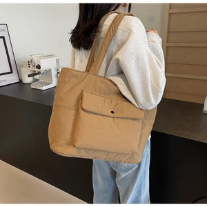 Lifestyle shot of khaki tote bag with front pocket showing large capacity and crinkled fabric
