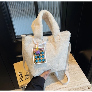 Detail of plush off-white bucket bag with fuzzy texture and cute calculator charm