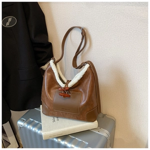 Detailansicht der braunen Bucket-Bag mit weißem Vliesbesatz und dekorativem Hornknopf