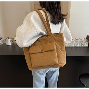 Back view of a model wearing a large caramel brown quilted tote bag in a cozy cafe