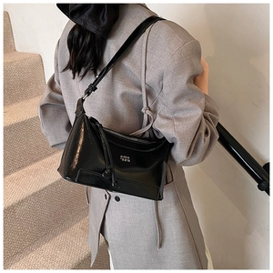 Detail showing high-gloss black patent leather texture and logo of the shoulder bag