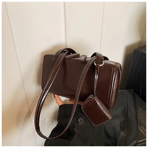 Detail of dark brown patent leather shoulder bag with matching mini coin purse accessory