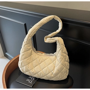 Close-up of quilted beige half-moon bag featuring soft diamond stitch and padded strap