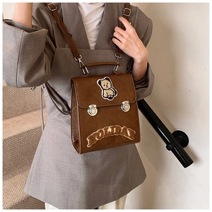 Detail of brown leather backpack with teddy bear patch and HOLIDAY letter embroidery