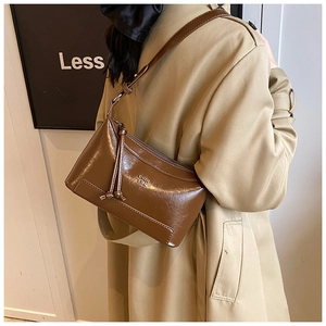 Close-up of vintage brown leather pillow bag with debossed logo and adjustable strap