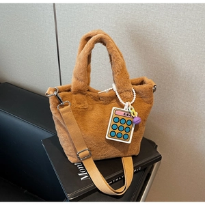Detail of soft brown plush bucket bag with wide strap and colorful calculator charm