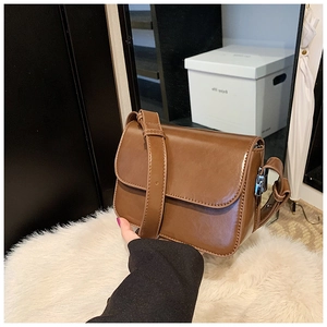 Detail of a brown vintage PU leather crossbody bag with a wide adjustable shoulder strap