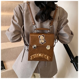Detail of vintage brown leather backpack with bear patch and holiday text embroidery