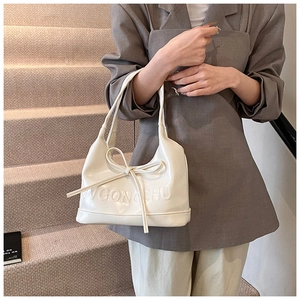 Vue détaillée du sac à main crème en cuir verni avec nœud et logo LVGONGZHU embossé