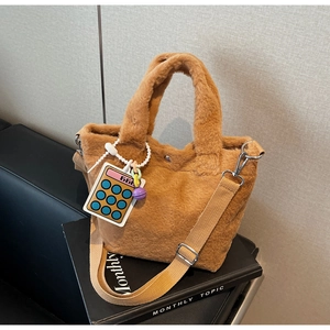 Detail of plush brown tote bag with woven strap and calculator pendant decoration