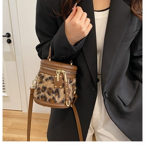 Detalle del bolso de cubo cilíndrico de leopardo con cremalleras doradas y remates de cuero