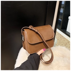 Detail view of caramel brown square shoulder bag with silver metal buckle and soft PU leather