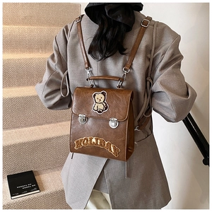 Detail of a brown vintage backpack with teddy bear patch and HOLIDAY embroidery