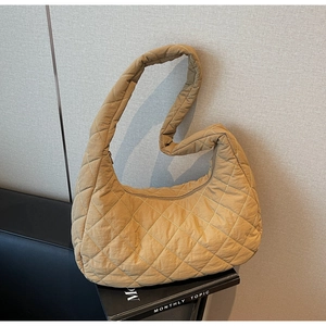Close-up of diamond-quilted texture on the mustard yellow padded crescent hobo bag