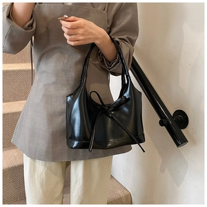 Gros plan détaillé d'un sac à main noir brillant orné d'un nœud décoratif élégant