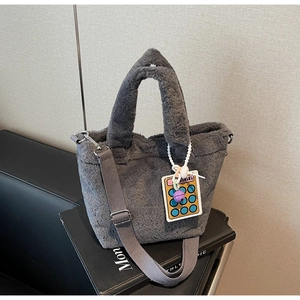 Detail view of grey plush bucket bag with cute calculator charm and canvas strap