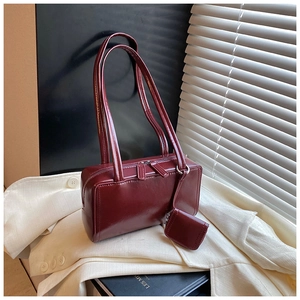 Detail of a dark red rectangular leather shoulder bag with matching mini pouch charm
